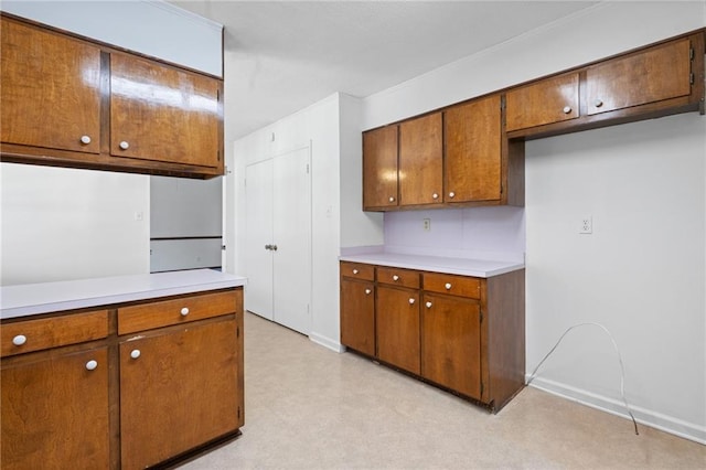 kitchen featuring brown cabinetry, baseboards, light countertops, and light floors