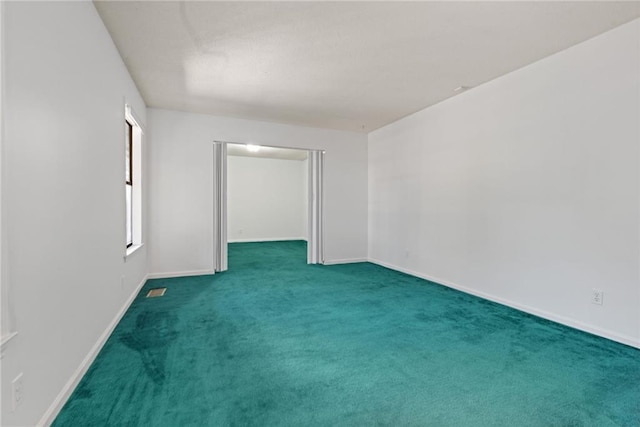 empty room featuring dark colored carpet and baseboards