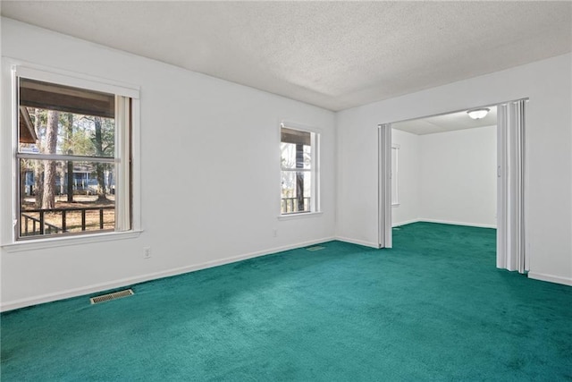 empty room featuring a textured ceiling, dark colored carpet, visible vents, and baseboards