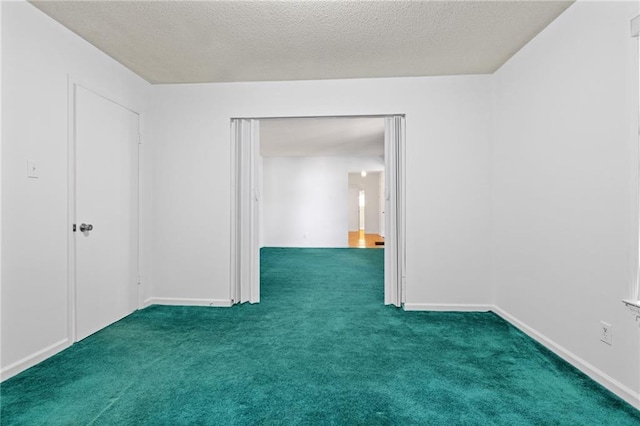 unfurnished room with dark colored carpet, a textured ceiling, and baseboards