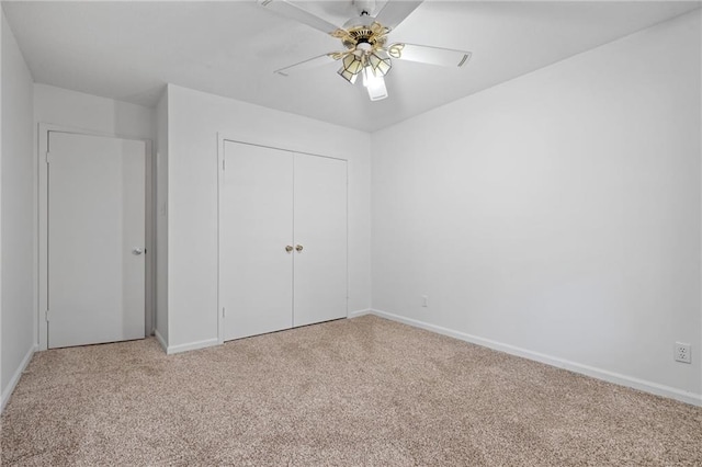 unfurnished bedroom featuring a ceiling fan, a closet, light carpet, and baseboards