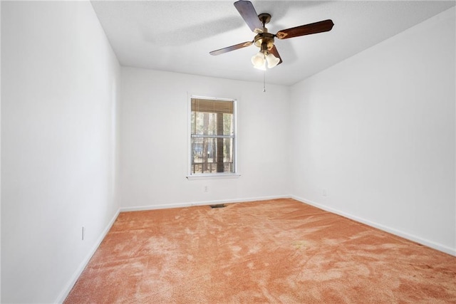 spare room featuring a ceiling fan, light carpet, and baseboards