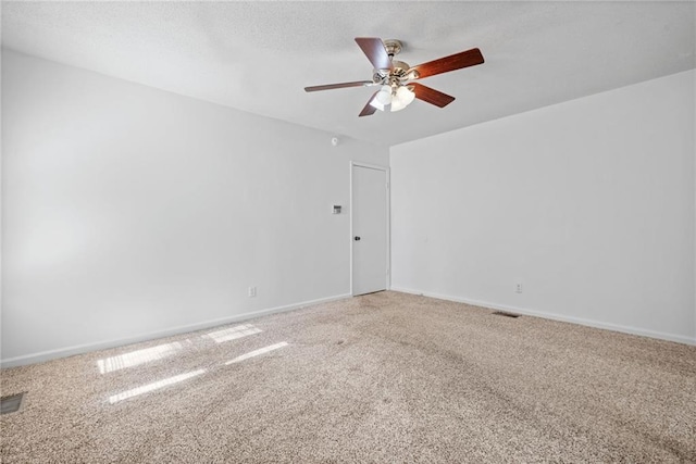 unfurnished room with carpet floors, visible vents, ceiling fan, and baseboards