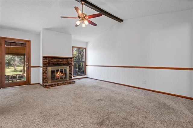 unfurnished living room featuring plenty of natural light, a brick fireplace, carpet flooring, and vaulted ceiling with beams