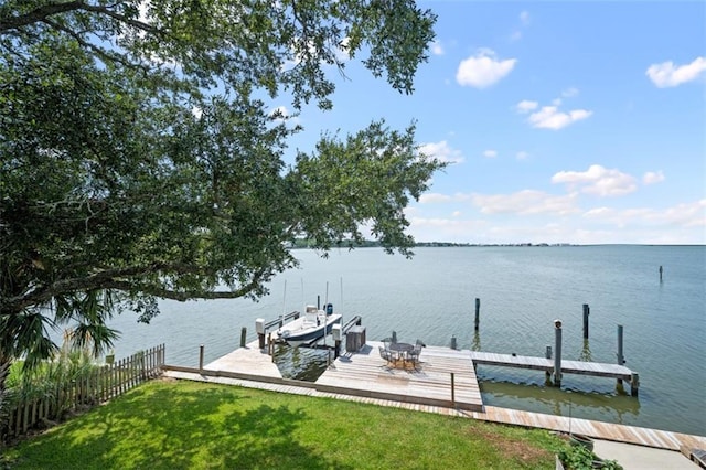 dock area with a water view, boat lift, and a yard