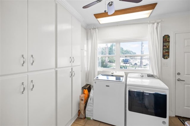 laundry area featuring cabinet space, washer and clothes dryer, a ceiling fan, crown molding, and light tile patterned flooring