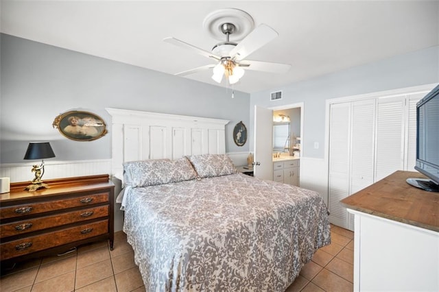 bedroom with a closet, wainscoting, visible vents, and light tile patterned floors