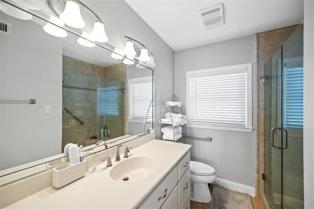 full bath featuring toilet, vanity, visible vents, baseboards, and a shower stall