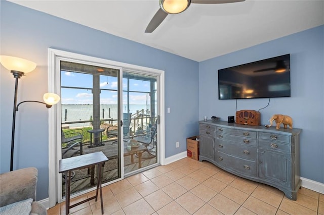 interior space with a ceiling fan, baseboards, and light tile patterned floors