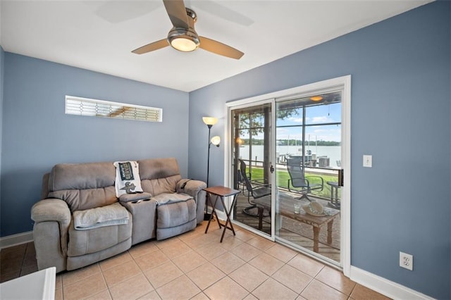 living area with a ceiling fan, a water view, baseboards, and light tile patterned floors