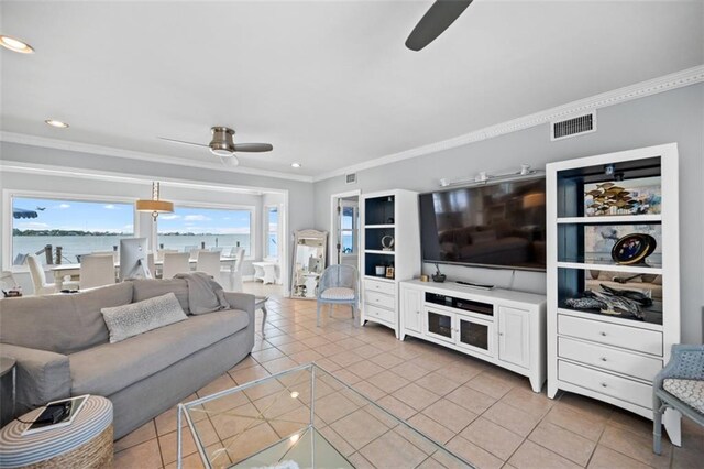 living area featuring crown molding, light tile patterned flooring, ceiling fan, and visible vents