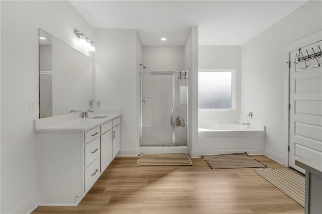 bathroom featuring hardwood / wood-style flooring, vanity, and separate shower and tub