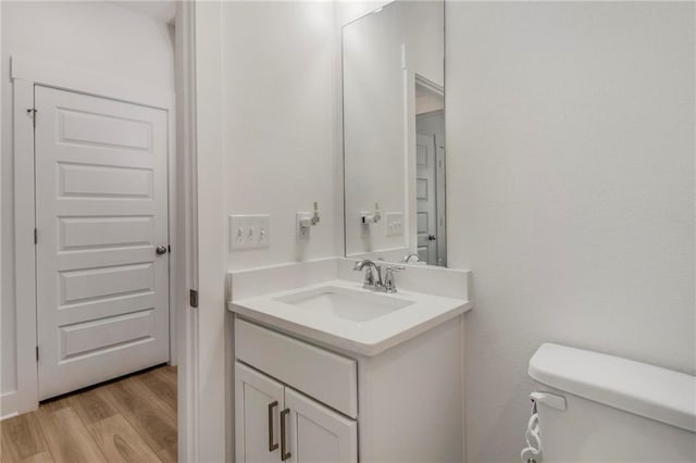 bathroom with toilet, vanity, and hardwood / wood-style flooring