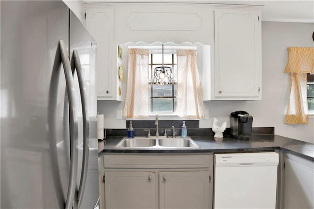 kitchen featuring dark countertops, white dishwasher, white cabinetry, and freestanding refrigerator