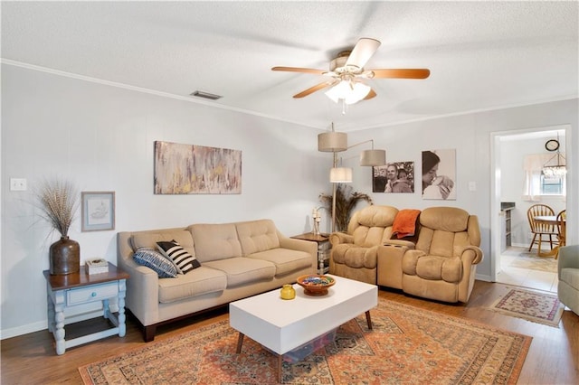 living room featuring ornamental molding, visible vents, ceiling fan, and wood finished floors