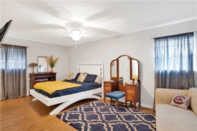 bedroom with ceiling fan, baseboards, and wood finished floors