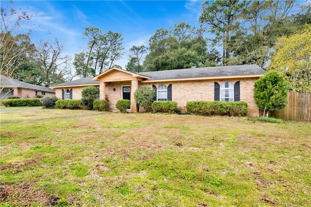 single story home featuring a front yard, brick siding, and fence