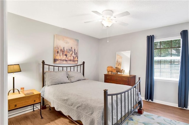 bedroom with ceiling fan, baseboards, and wood finished floors