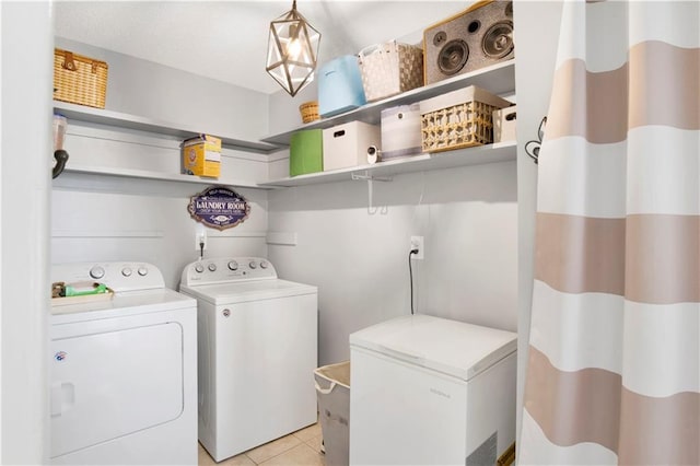 clothes washing area featuring laundry area, washer and clothes dryer, and light tile patterned flooring