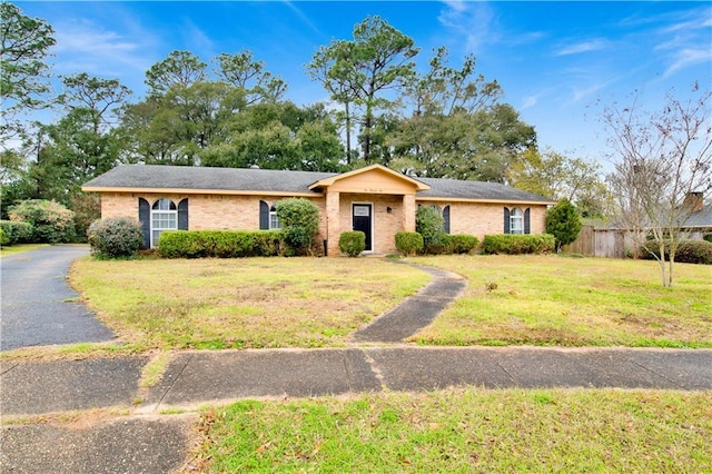 view of front of home with a front yard, brick siding, and fence