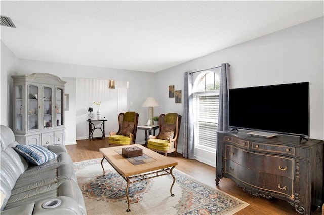 living area featuring light wood finished floors, visible vents, and baseboards