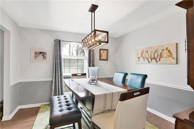 dining room featuring a chandelier, wood finished floors, and baseboards