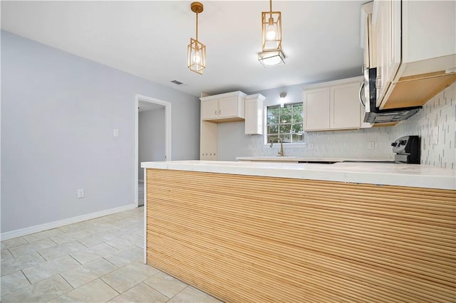 kitchen featuring tasteful backsplash, kitchen peninsula, stove, pendant lighting, and light tile patterned floors