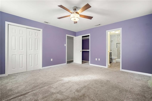 unfurnished bedroom featuring connected bathroom, light colored carpet, and ceiling fan