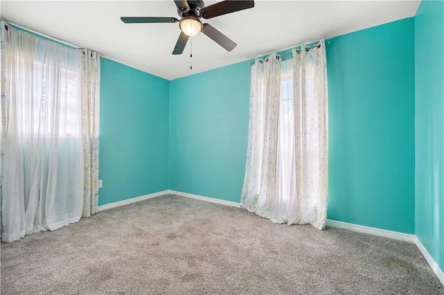 carpeted empty room with ceiling fan and plenty of natural light