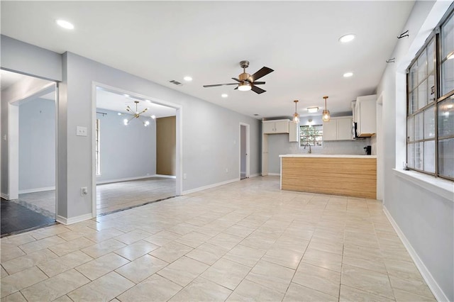 kitchen with sink, white cabinetry, hanging light fixtures, and light tile patterned flooring