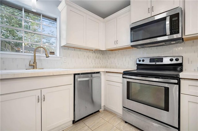 kitchen with sink, white cabinetry, stainless steel appliances, and light tile patterned floors