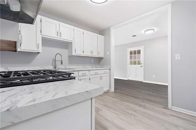 kitchen with stove, light wood-type flooring, ventilation hood, sink, and white cabinetry