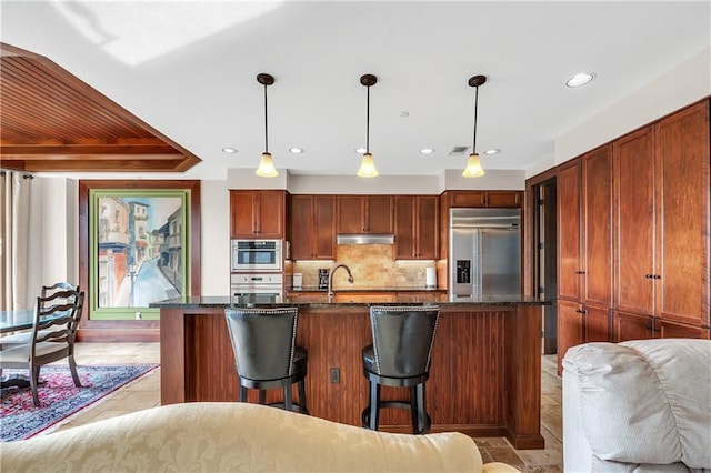 18269 Colony Dr Unit 405, Fairhope, AL 36532 - kitchen with stainless steel appliances, under cabinet range hood, a kitchen breakfast bar, tasteful backsplash, and decorative light fixtures