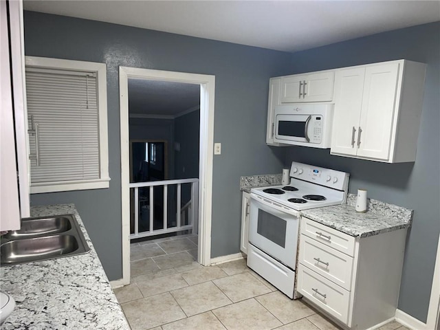 kitchen with white cabinets, light countertops, a sink, white appliances, and baseboards
