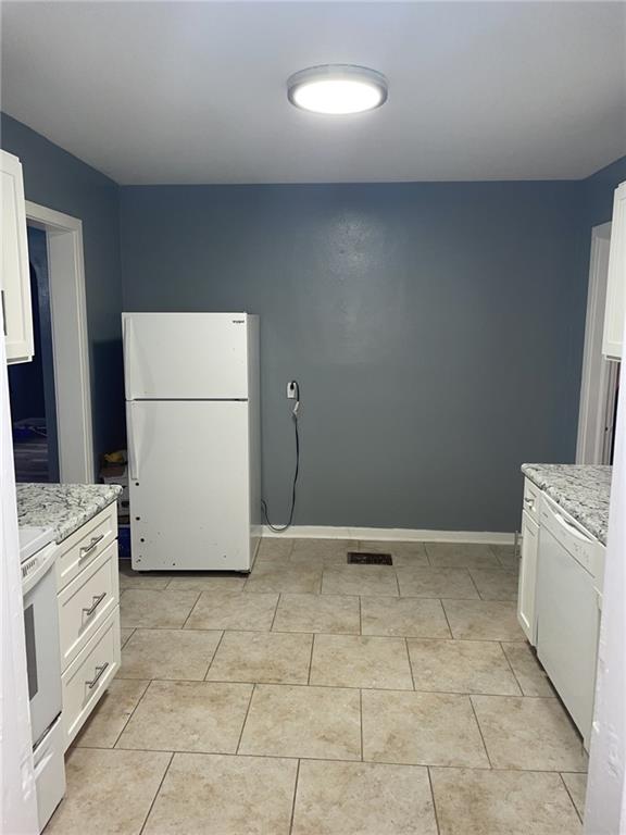 kitchen featuring baseboards, white cabinetry, light stone counters, and white appliances