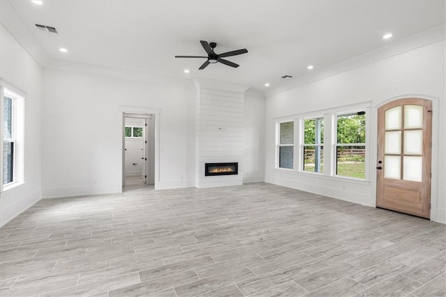 unfurnished living room with ceiling fan, a large fireplace, ornamental molding, and brick wall