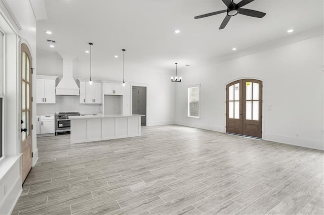 unfurnished living room with ornamental molding, light wood-type flooring, and ceiling fan with notable chandelier