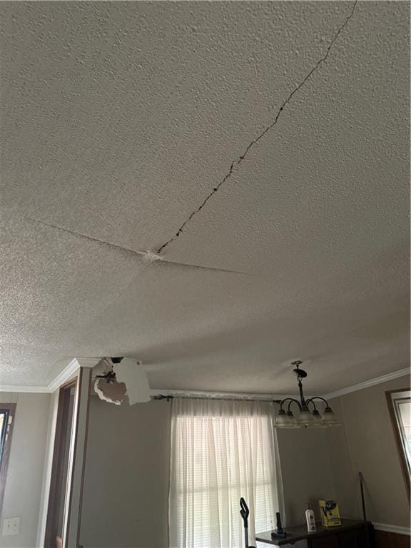 interior details with crown molding, a textured ceiling, and an inviting chandelier