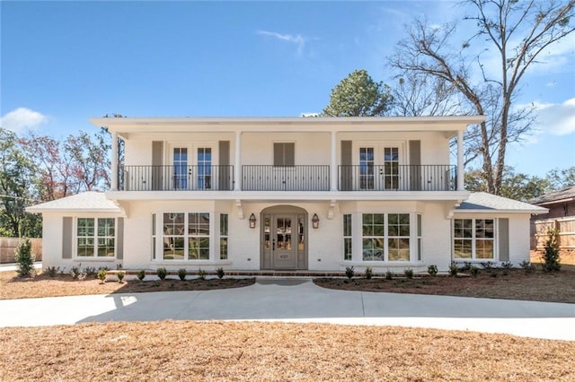 view of front of house featuring brick siding, french doors, and a balcony