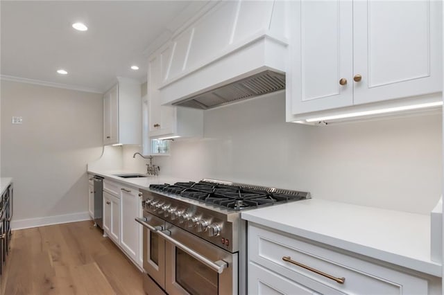 kitchen with custom exhaust hood, double oven range, white cabinetry, and a sink