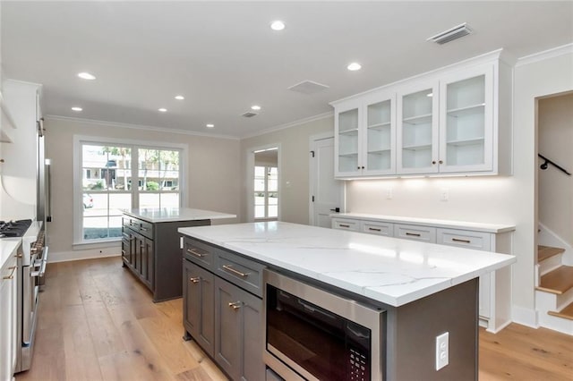 kitchen with stainless steel appliances, ornamental molding, white cabinetry, and a center island