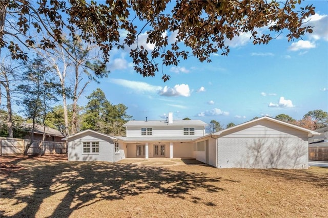 rear view of house featuring a patio area, fence, and brick siding