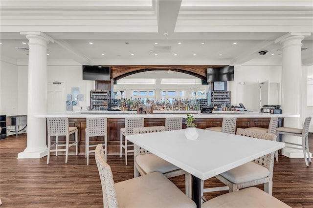 dining area featuring a community bar, decorative columns, ornamental molding, wood finished floors, and recessed lighting