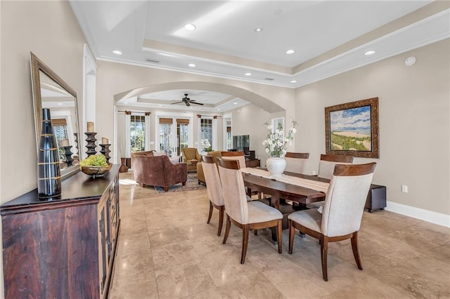 dining space with baseboards, arched walkways, ornamental molding, a tray ceiling, and recessed lighting