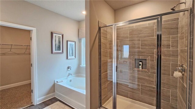full bath featuring a walk in closet, baseboards, a shower stall, and a bath