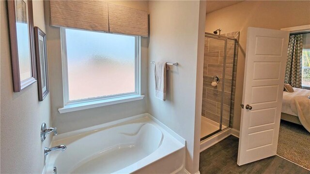bathroom with wood finished floors, ensuite bathroom, a bath, and a stall shower