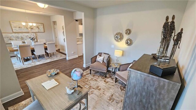 living area featuring baseboards, an inviting chandelier, and wood finished floors