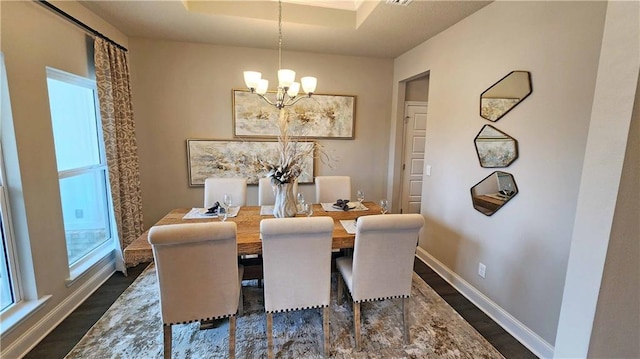 dining room featuring an inviting chandelier, baseboards, dark wood-style flooring, and a raised ceiling