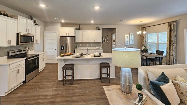 kitchen featuring decorative backsplash, a breakfast bar area, recessed lighting, appliances with stainless steel finishes, and a notable chandelier
