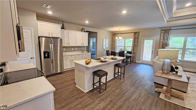 kitchen with a breakfast bar area, stainless steel refrigerator with ice dispenser, white cabinets, and a wealth of natural light